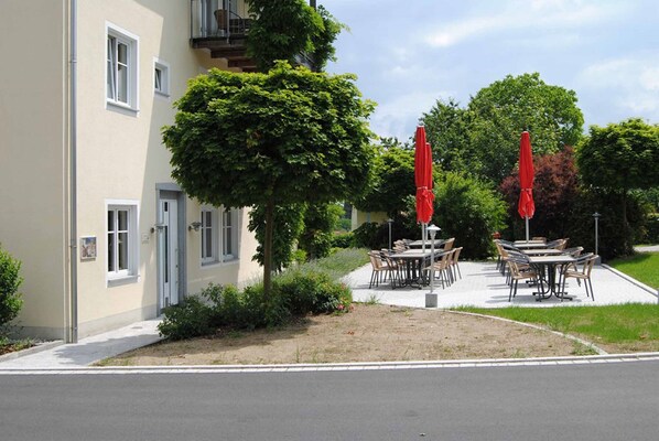 A building with outdoor seating and a tree in front. - Zum Kirchenwirt (Neukirchen vorm Wald)