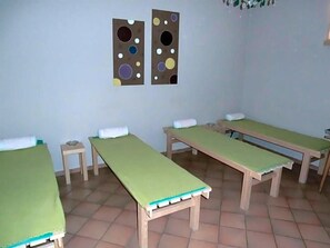 Una habitación con cuatro camas individuales, cada una con cubrecama verde y almohadas blancas. Hay dos obras de arte colgadas en la pared sobre las camas.