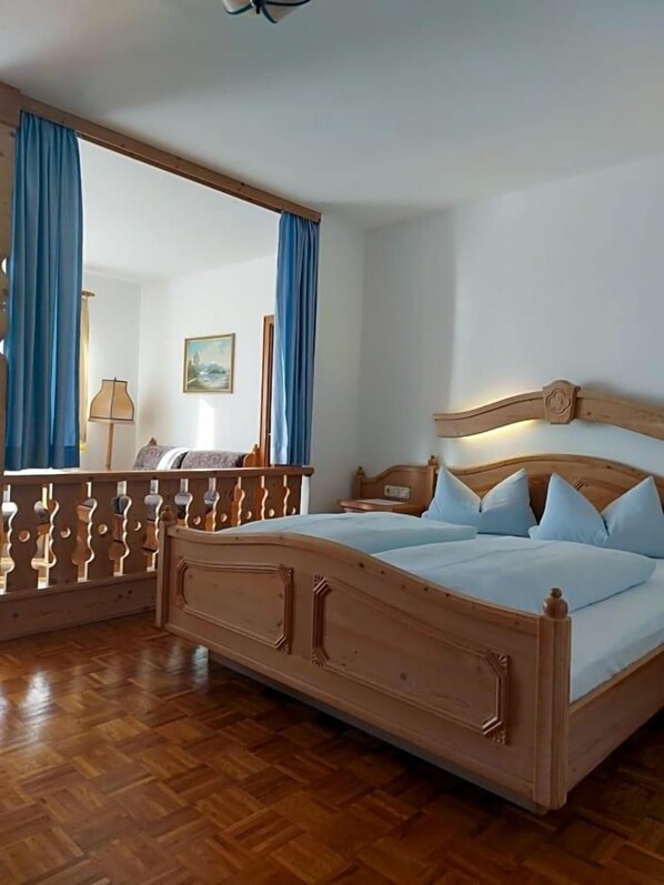 A wooden bed with a headboard, a nightstand, a mirror, and blue curtains.
