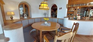 Un comedor con una mesa redonda, sillas de madera, un banco y una barra.