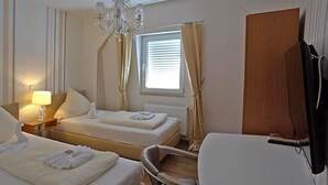 A hotel room with two beds, a chair, a TV, and a window with curtains. - Hotel Zum Wersehof (Ahlen)