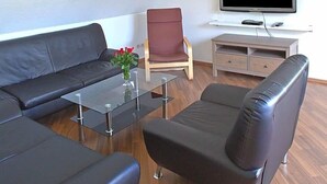 A modern living room with a sofa, armchair, and a coffee table. - Hotel Zum Wersehof (Ahlen)