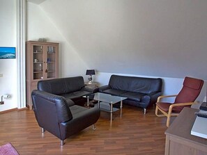 A living room with a sofa, a coffee table, a red chair, and a cabinet.