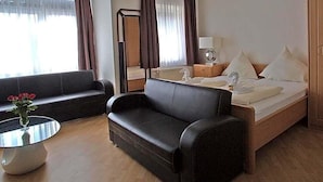 A hotel room with a bed, a sofa, a small table with a vase, and a mirror. - Hotel Zum Wersehof (Ahlen)