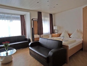 A hotel room with a bed, a sofa, a small table with a vase, and a mirror. - Hotel Zum Wersehof (Ahlen)