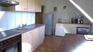 A kitchen with a stove, oven, sink, and microwave. There is a dining table and chairs. - Hotel Zum Wersehof (Ahlen)