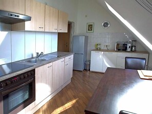 A kitchen with a stove, oven, sink, and microwave. There is a dining table and chairs. - Hotel Zum Wersehof (Ahlen)