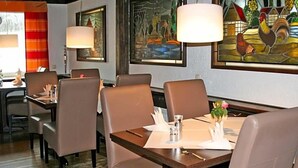A restaurant interior with wooden tables, cushioned chairs, and framed artwork on the walls. - Hotel Zum Wersehof (Ahlen)