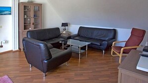 A living room with a sofa, a coffee table, a red chair, and a cabinet. - Hotel Zum Wersehof (Ahlen)