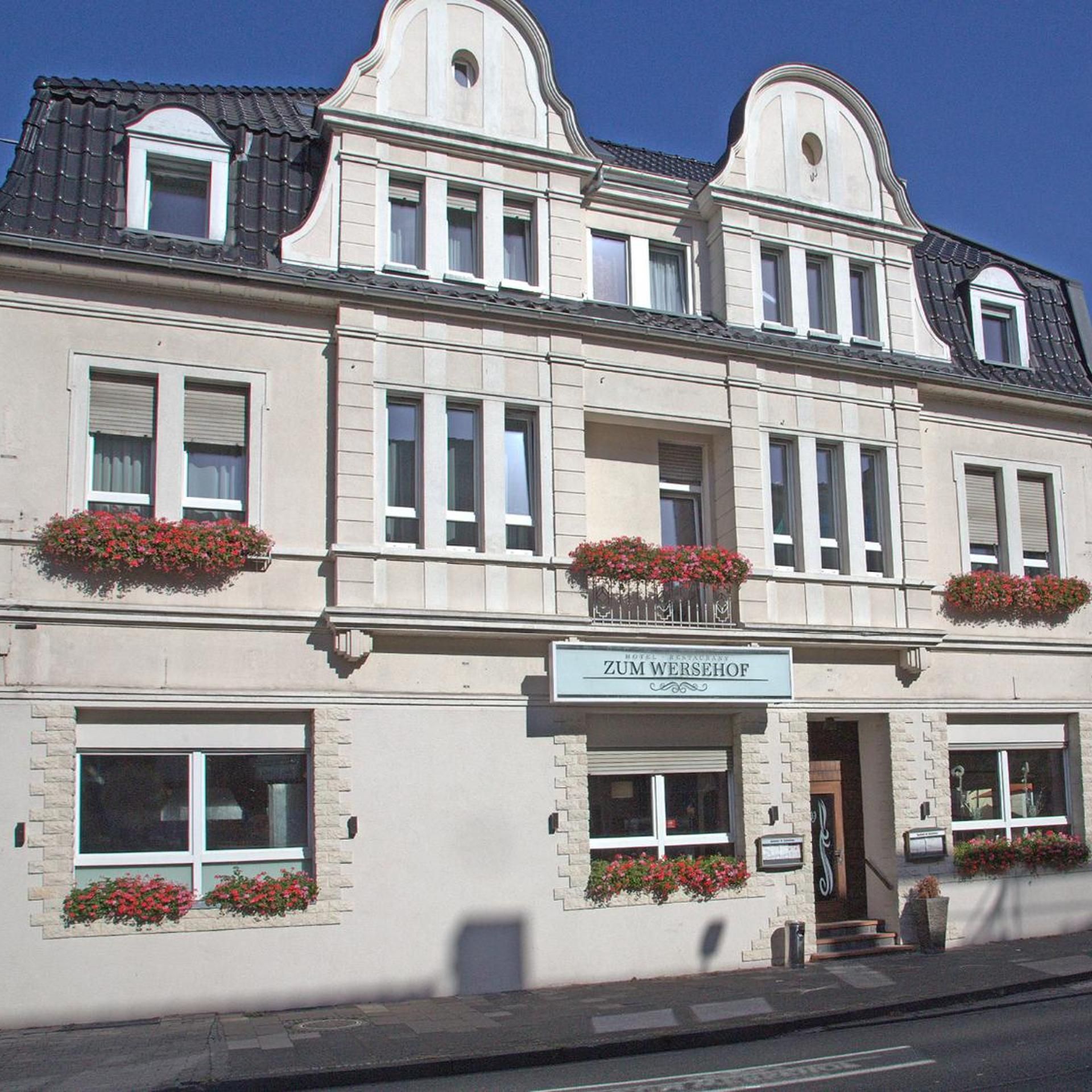 A hotel with a classic facade, multiple windows, and flower boxes on the ground floor.