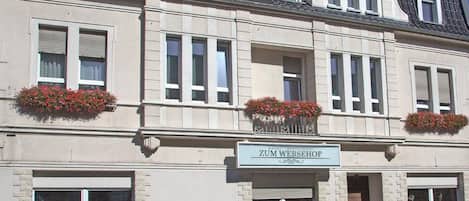 A hotel with a classic facade, multiple windows, and flower boxes on the ground floor.