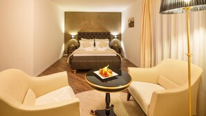 A hotel room with a bed, two armchairs, a small table with fruit, and a floor lamp. - Business Hotel First (Feusisberg)
