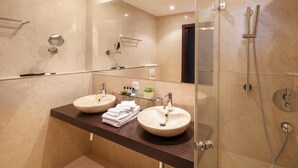 Une salle de bain moderne avec deux lavabos, une douche à parois de verre et un grand miroir.