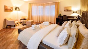 A hotel room with a large bed, a desk, a chair, a sofa, and a window with curtains. - Business Hotel First (Feusisberg)