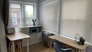 A compact kitchen with white cabinets, a microwave, a small trash bin, and a window with blinds. - Lovely, cozy Beacon guest suite with portable kitchen in Squirrel Hill (Pittsburgh)