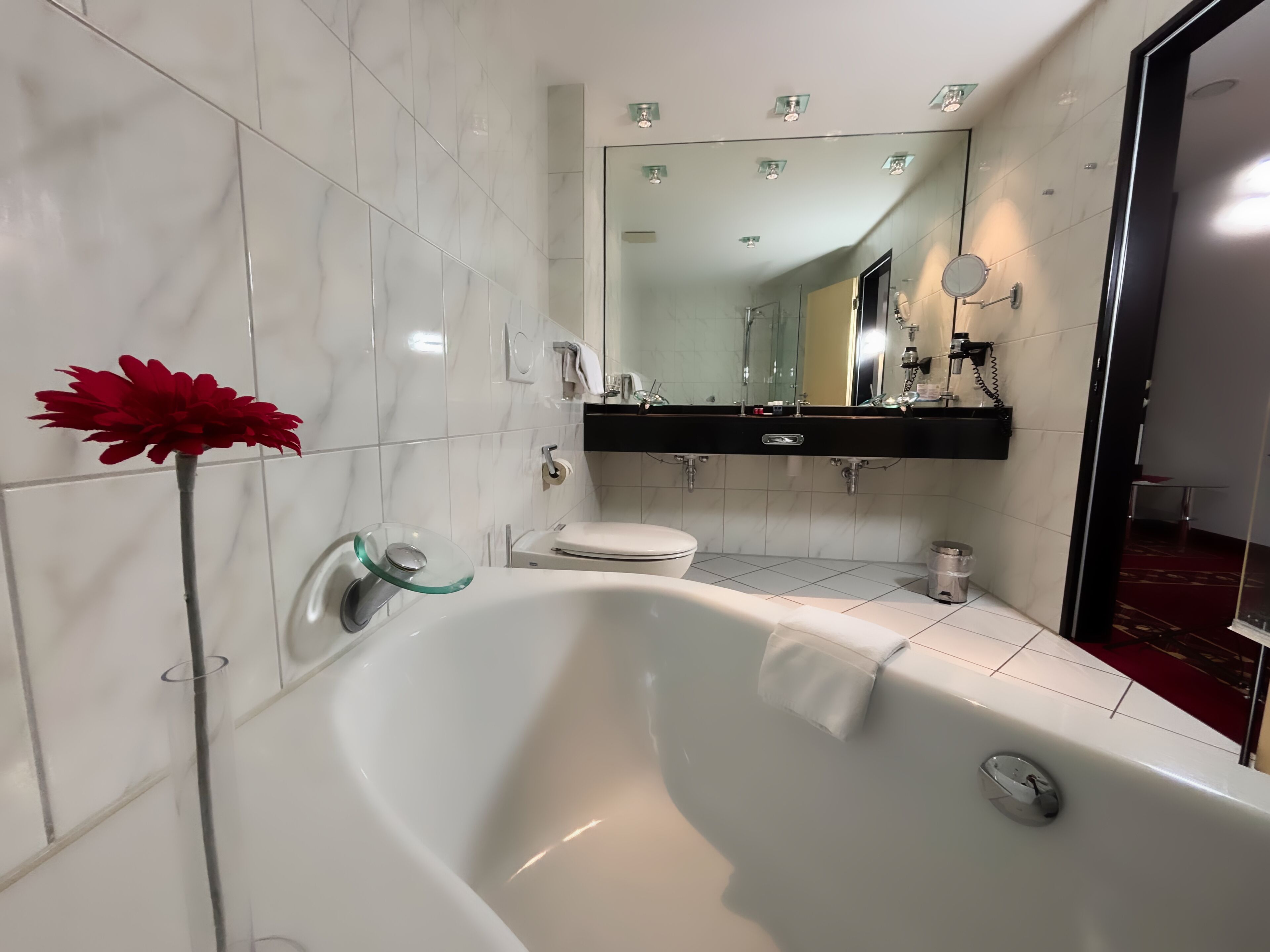 Un baño moderno con una bañera independiente, cabina de ducha con mampara de vidrio y un espejo grande sobre el lavamanos.