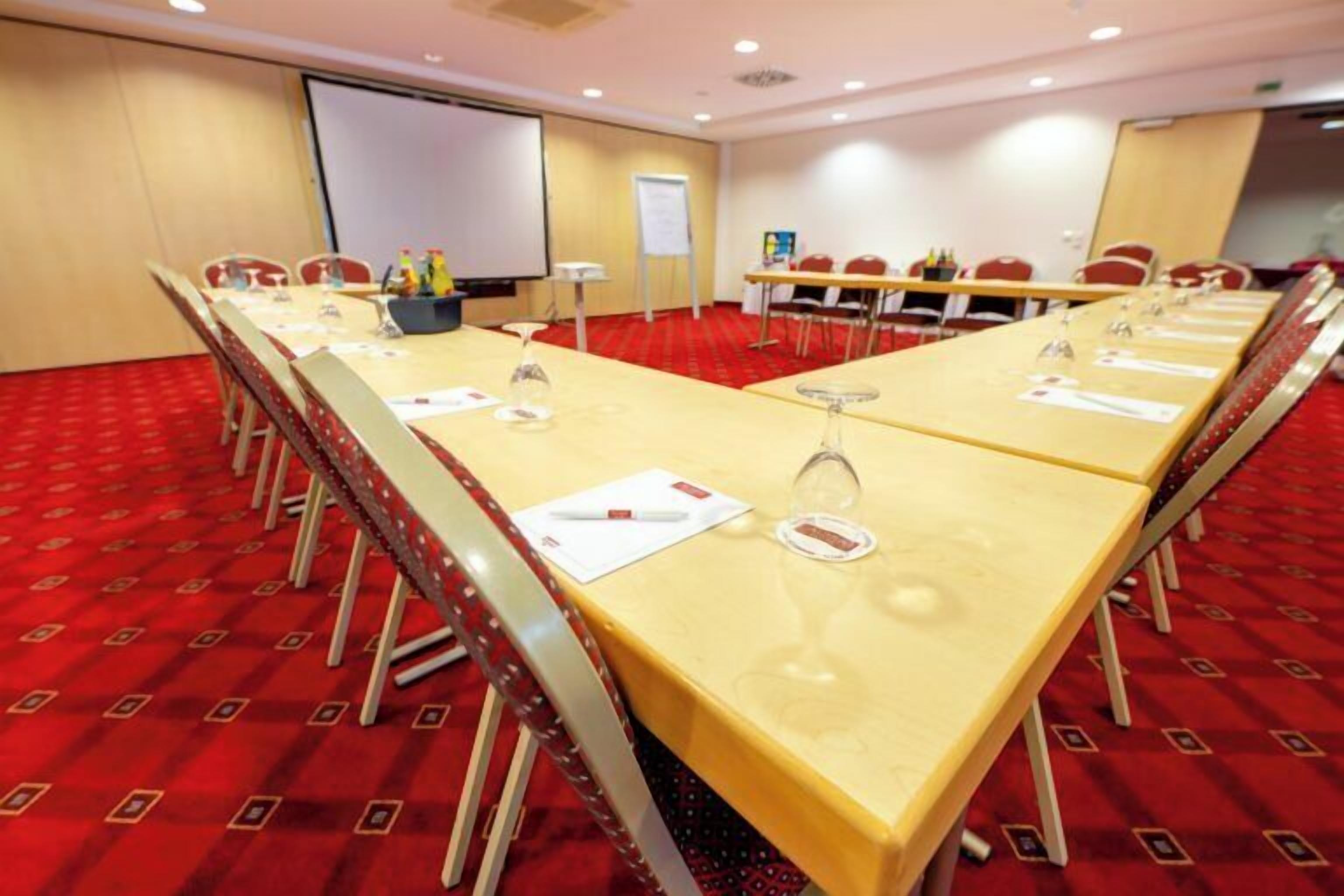 A conference room with a long table, chairs, a projector screen, and a whiteboard.