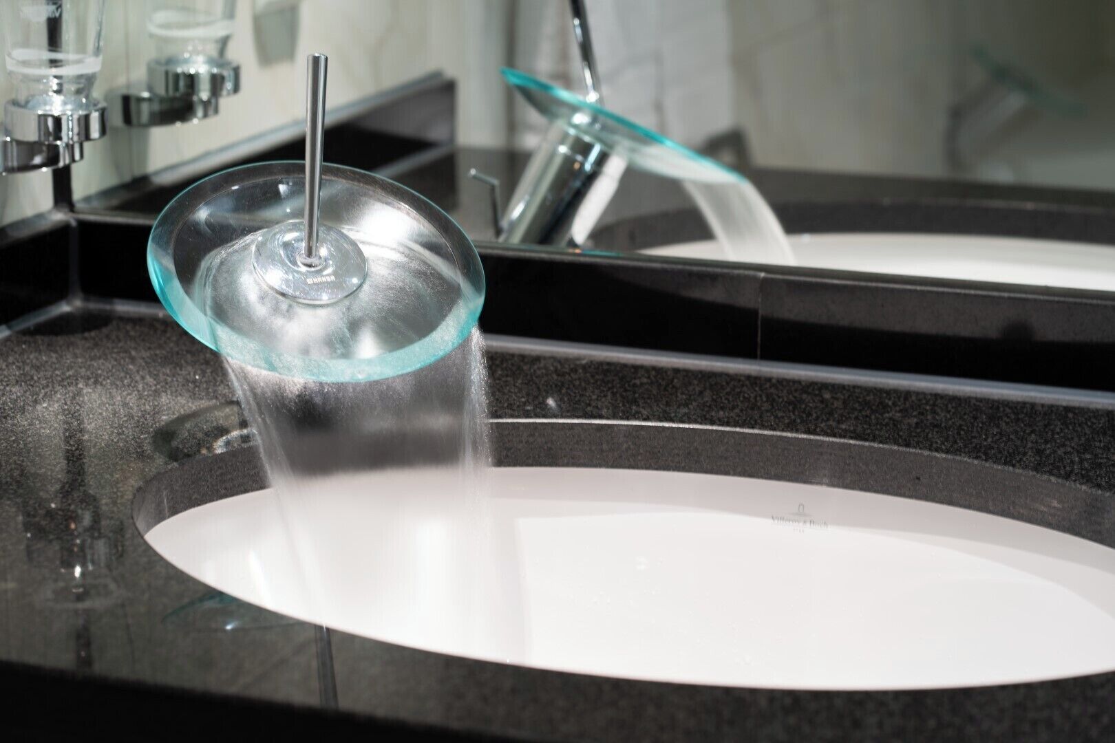 A modern bathroom with a glass-covered sink and a chrome faucet.