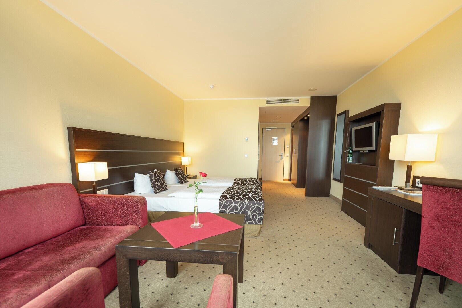 Een hotelkamer met een bed, een bureau, een stoel, een televisie en een tv-meubel.
