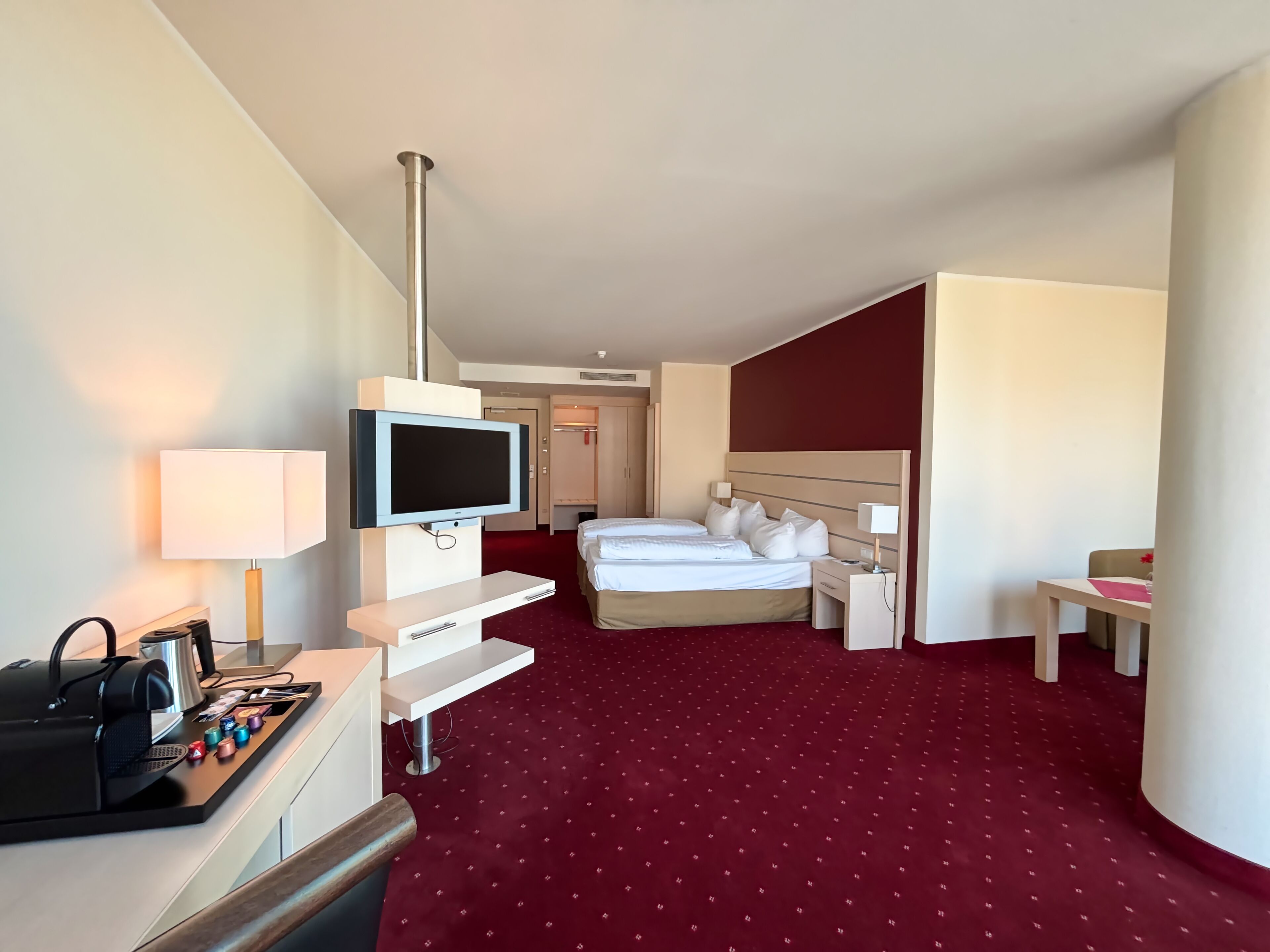 Une chambre d’hôtel équipée d’un lit, d’une table de chevet, d’une télévision, d’un bureau avec un ordinateur et d’une machine à café.