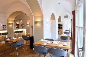 Ein moderner Essbereich mit mehreren Tischen und Stühlen, gewölbten Decken und einer Bar mit einer Theke.