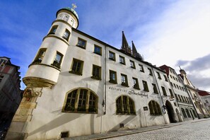 Ein historisches Gebäude mit einem Turm, Rundbogenfenstern und einem Schild, das es als Restaurant und Hotel kennzeichnet.