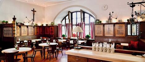 Un interior de restaurante con varias mesas, sillas y una zona de bar.