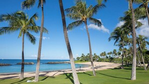 A golf course with palm trees and a beach view.