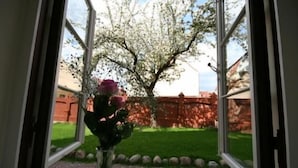 Vista por una ventana con un jarrón de flores y un árbol afuera.