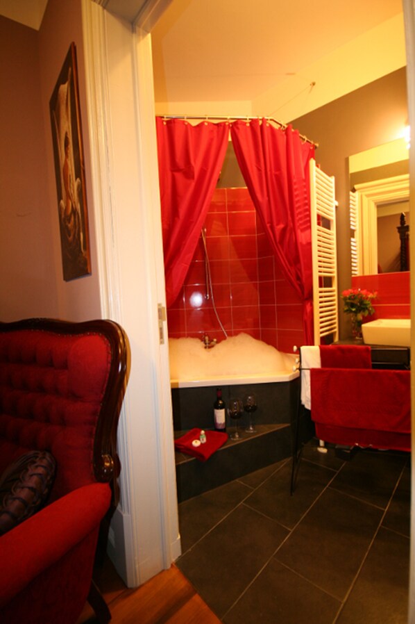 Un baño con una bañera, una silla y una cortina, todo en rojo.