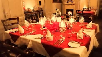 Una mesa de comedor dispuesta para una comida, con sillas, una chimenea y un cuadro en la pared.