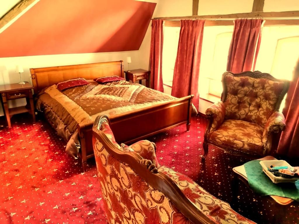 Ein Schlafzimmer mit einem großen Bett, einem Nachttisch aus Holz, einem Sessel und einem kleinen Tisch mit Tablett.