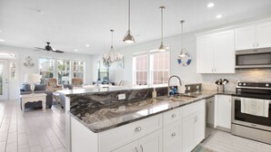 Een moderne keuken met witte kasten, een marmeren aanrechtblad en roestvrijstalen apparatuur.