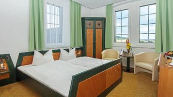 A hotel room with a large bed, a desk, a chair, and a view of the outdoors.