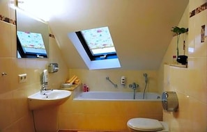 Ein Badezimmer mit Waschbecken, Toilette, Badewanne und einem Oberlicht.