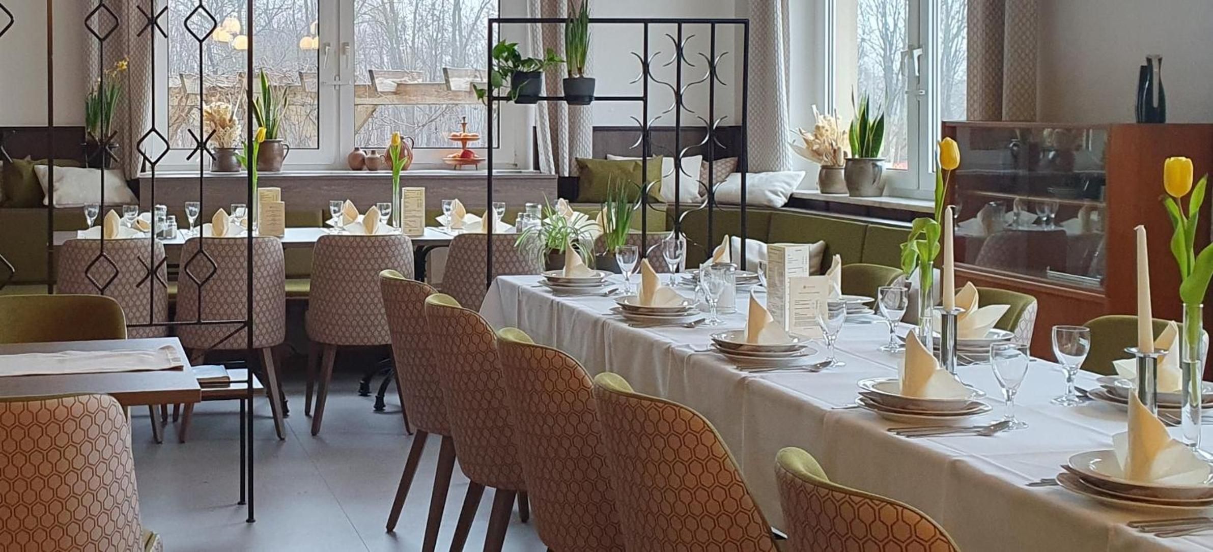 En restaurant med dækketøjsdækket borde, stole og en dekorativ metaladskillelse.