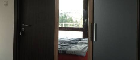 Una habitación con una cama, un armario y una ventana.