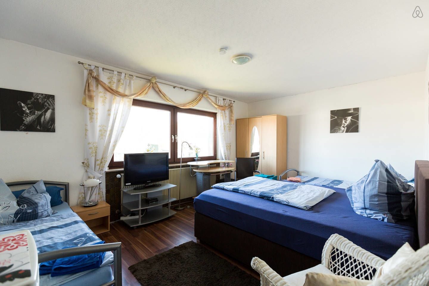 Une chambre à coucher avec un lit, un bureau avec un ordinateur, une télévision et une chaise.