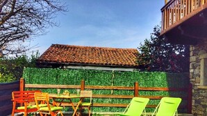 Un patio con cerramiento de madera, una mesa con sillas y dos sillones verdes.