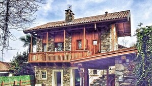 Una casa de piedra de dos pisos, con un balcón de madera y una escalera de piedra que conduce a la entrada.