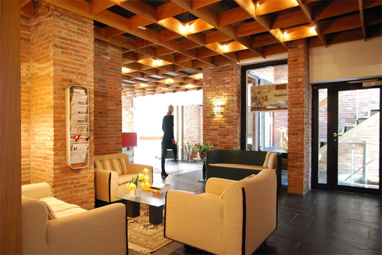 Eine Lobby mit Backsteinwänden, einer Holzbalkendecke und einer Sitzecke mit Sofas und einem Couchtisch.