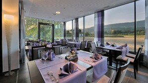A restaurant with tables set for dining, large windows offering a view of the countryside. - Hotel Al Ponte (Wiedlisbach)