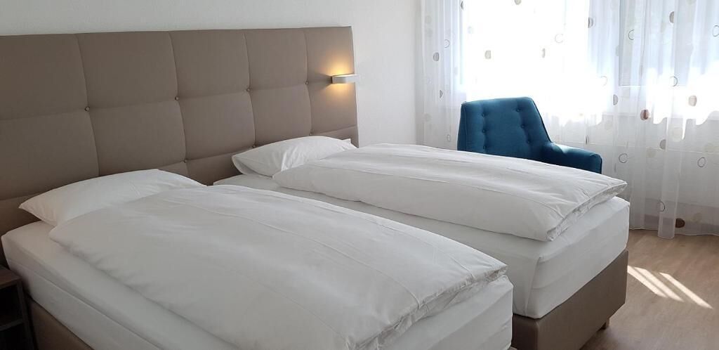 A double bed with a headboard, a bedside table, and a chair.