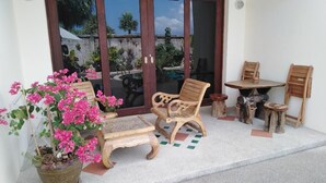 Un patio con una silla de madera, una mesita y una planta en maceta.