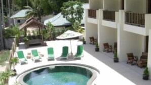 Zona de piscina con sillas de descanso y un edificio al fondo.