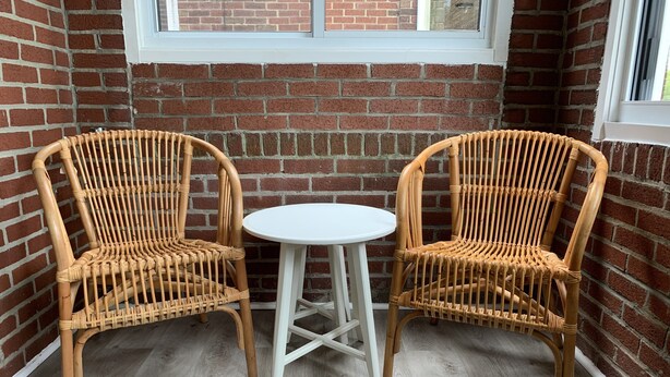 Two wicker chairs with a white table between them, set against a brick wall with a window above. - Lovely, cozy Murray guest suite in Squirrel Hill  (Pittsburgh)
