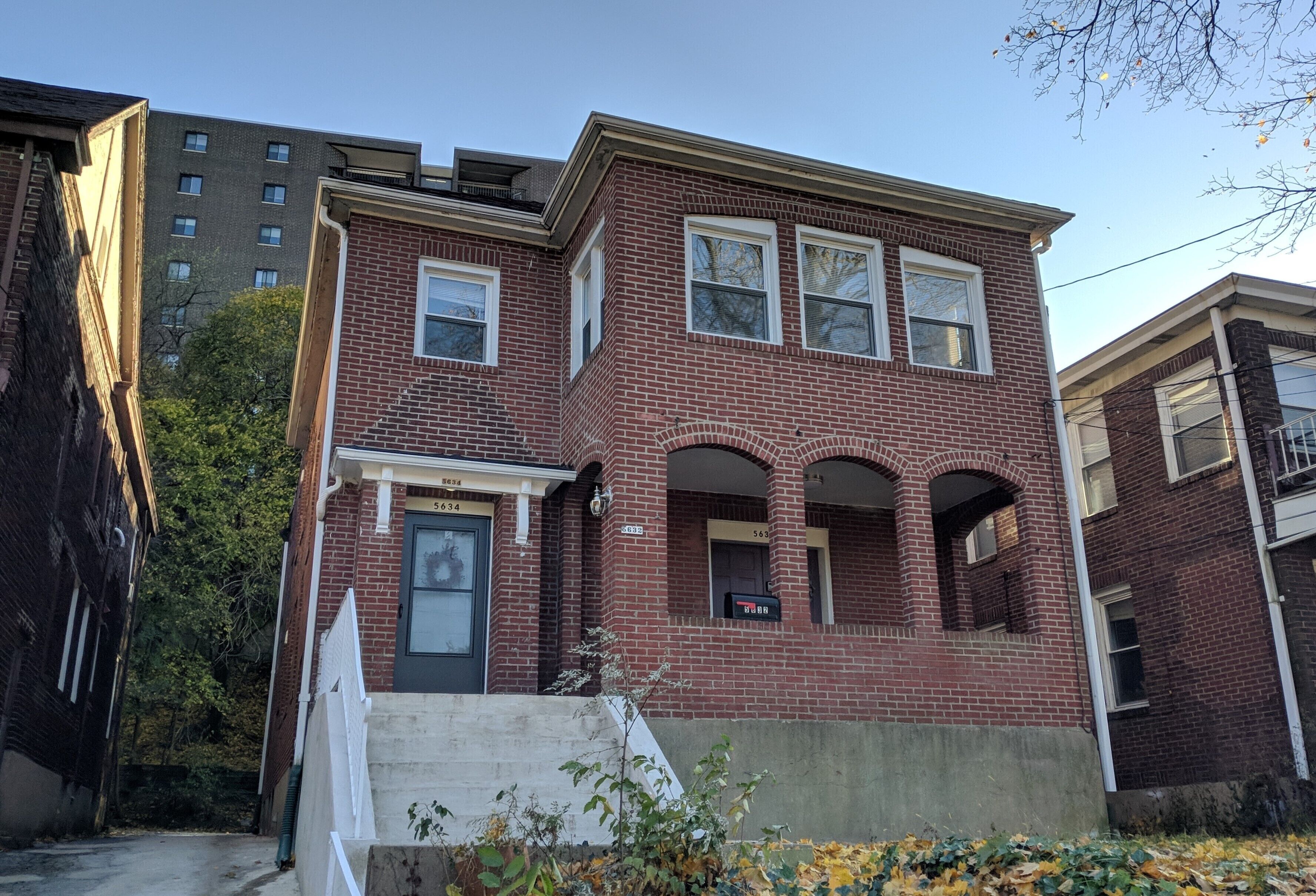 A two-story brick building with a front entrance, a small porch, and a visible mailbox.