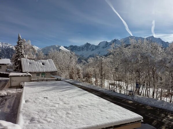 A snow-covered mountain landscape with a building featuring a sloped roof and a snow-covered ground. - appartment 3 people (Passy)
