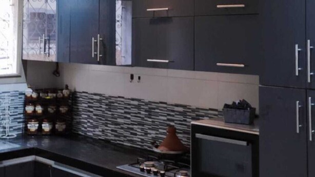 A modern kitchen with dark cabinetry, a tiled backsplash, and a gas stove. - ^^ Superb apt near the beach  (Agadir)