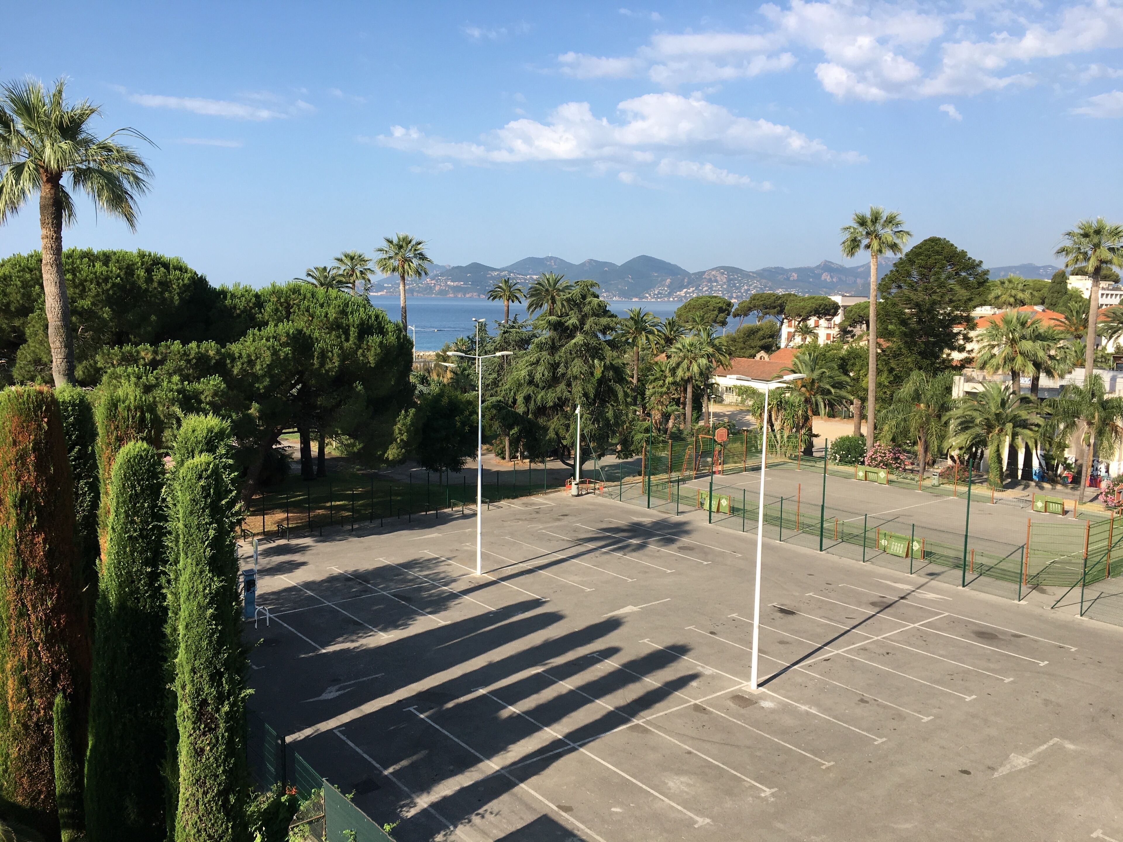 A tennis court with a clear view of the sea and mountains in the background.